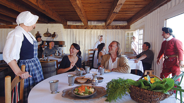 Visitors dining with period-costumed staff at Grandchamp House in the Fortress of Louisbourg Visitors dining with period-costumed staff at Grandchamp House in the Fortress of Louisbourg